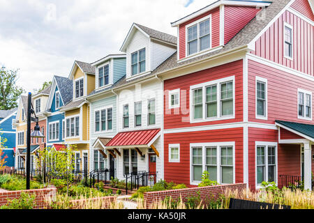 Riga di colorati, rosso, giallo, blu, bianco, verniciato di verde case residenziali, case, case in mattoni con patio giardino in estate Foto Stock