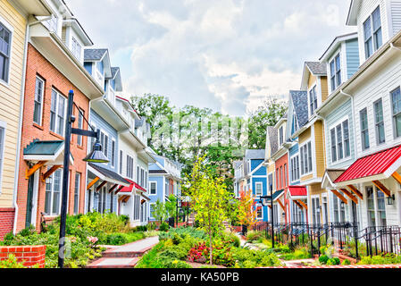 Riga di colorati, rosso, giallo, blu, bianco, verniciato di verde case residenziali, case, case in mattoni con patio giardino in estate Foto Stock
