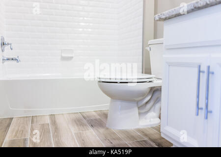 Bianca e moderna pianura pulire wc bagno vasca con doccia piastrelle e pavimenti in legno duro con staging in modello di casa di staging, casa o appartamento Foto Stock