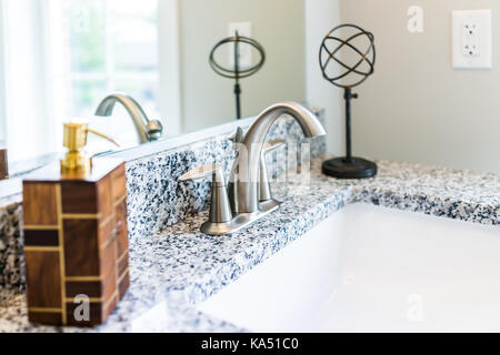 Primo piano di una moderna stanza da bagno lavandino con bancone in granito, specchio, dispenser di sapone pompa e rubinetto nel modello di staging home, appartamento o casa Foto Stock