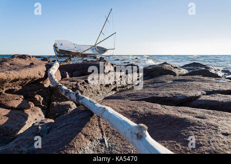 Barca a vela, intrecciato lungo la costa sulla scogliera della Sardegna nel mar Mediterraneo. Foto Stock