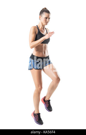 Dura determinata atleta femminile jogging e guardando avanti. metà profilo. corpo pieno lunghezza ritratto isolato su bianco di sfondo per studio. Foto Stock