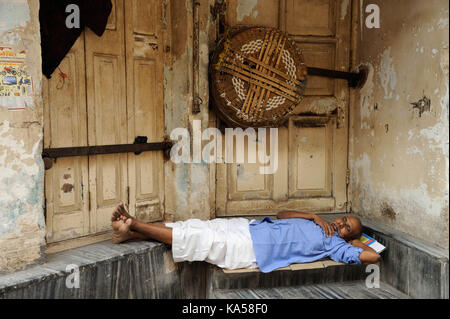 Senzatetto uomo dorme nella parte anteriore dello sportello, Mumbai, Maharashtra, India, Asia Foto Stock