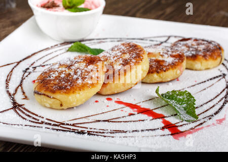 Pancake fatti in casa con fragole e salsa al cioccolato su uno sfondo di legno. Foto Stock