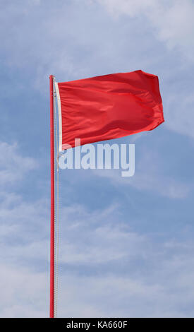 Battenti bandiera sventola indicante uno stato di pericolo e di allarme con sullo sfondo di un cielo blu Foto Stock