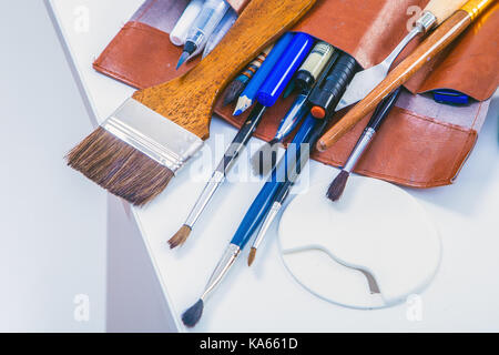 Close-up brown custodia in pelle con spazzole di diverse dimensioni su un tavolo bianco, vista dall'alto Foto Stock