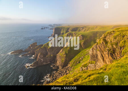 Mull of oa, Islay, Scozia, in serata con una bella luce calda, nebbia è comming in oltre la scogliera, gren erba sul terreno, Islay, SCOZIA Foto Stock