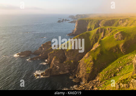 Mull of oa, Islay, Scozia, in serata con una bella luce calda, nebbia è comming in oltre la scogliera, gren erba sul terreno, Islay, SCOZIA Foto Stock