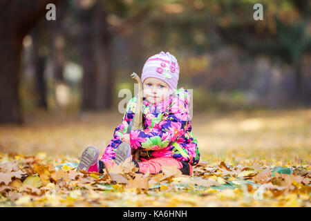 Bambina gioca con il giocattolo dinosauro nel parco di autunno Foto Stock