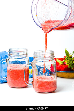 Versare il succo di pomodoro da un frullatore per un vaso Foto Stock