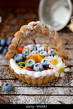 Piccolo a forma di cesto crostata con pesche e fragole con panna Foto Stock