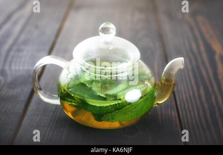 Teiera con il tè alla menta vicino sul tavolo. infusioni di erbe e cibo sano. Foto Stock