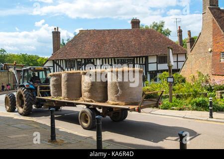 Le balle di paglia su un trattore di andare alla fattoria attraverso la pittoresca città di battaglia, East Sussex, Inghilterra, Regno Unito. Foto Stock