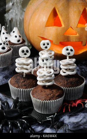 Scheletro di pretzel nel cioccolato al latte e marshmallow in un muffin, su un tavolo in onore di halloween Foto Stock