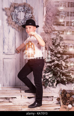 A dieci anni ragazzo che soggiornano presso dorstep, guardando avanti e lanterna tenuta in mano a natale Foto Stock