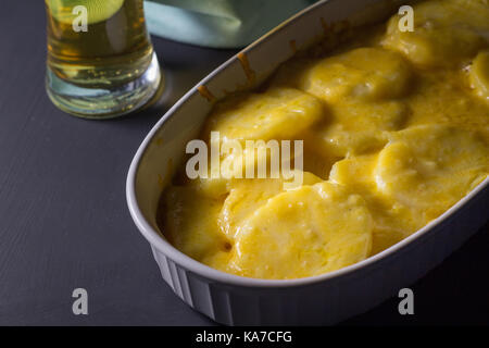 Cheesy potato cuocere vicino sul rustico sfondo - Immagine verticale con lo spazio di testo Foto Stock