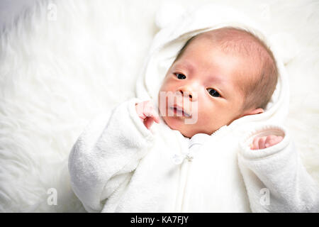 Carino piccolo ragazzo, da più di un mese, in abito bianco Foto Stock