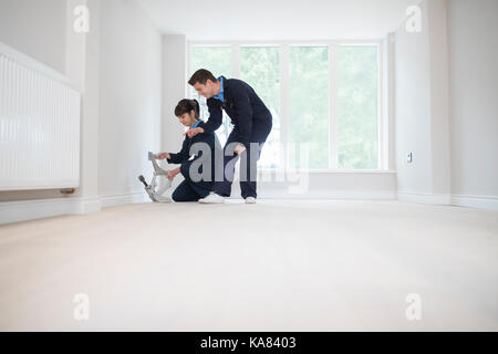 Carpenter e apprendista femmina la posa di un nuovo pavimento in legno in casa Foto Stock