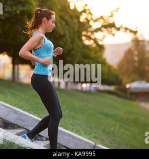 Sorridente giovane donna sportivo scendendo su scale di formazione nella mattina. Idoneità ragazza di andare giù per le scale a fare jogging nel parco Foto Stock