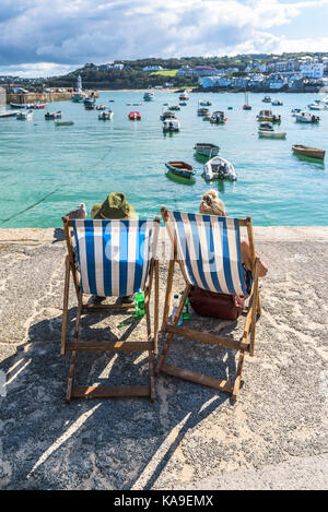 St ives - vacanzieri in rilassanti sedie a sdraio sul Quayside e godendo della vista su St ives harbour cornwall. Foto Stock