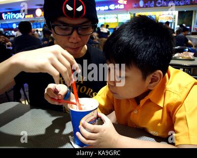 Mandaluyong city, Filippine - 24 settembre 2017: due ragazzi condividono un gelato in un food court. Foto Stock