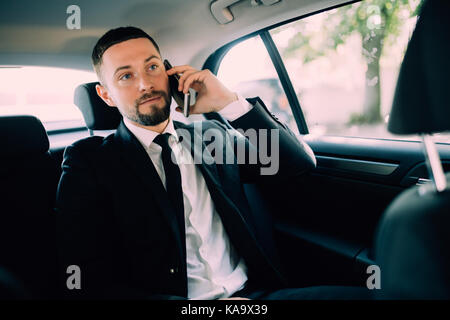 Imprenditore lavora nel sedile posteriore di una macchina Foto Stock