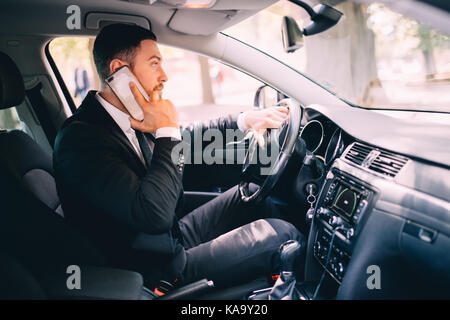 Business driver uomo parlare telefono bianco auto drive Foto Stock