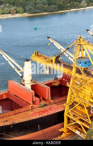 La gru scarica il minerale di ferro al porto. Il commercio di materie prime. il lavoro in un porto del mar Baltico Foto Stock