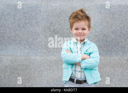 Moda bimbo in camicia di menta in posa su un muro grigio Sfondo. trendy boy permanente sulla strada. Foto Stock