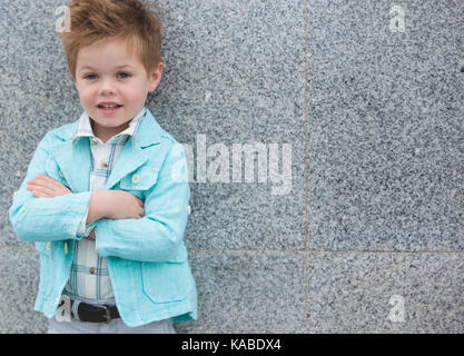 Moda bimbo in camicia di menta in posa su un muro grigio Sfondo. trendy boy permanente sulla strada. Foto Stock