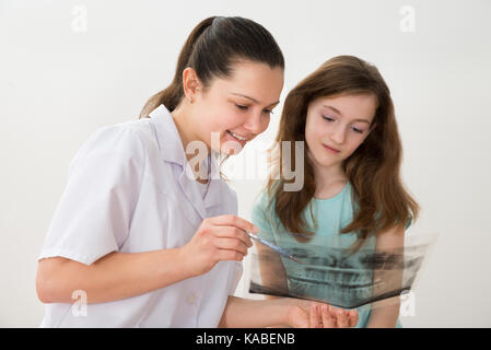 Giovani femmine dentista mostra raggi x al paziente in clinica Foto Stock