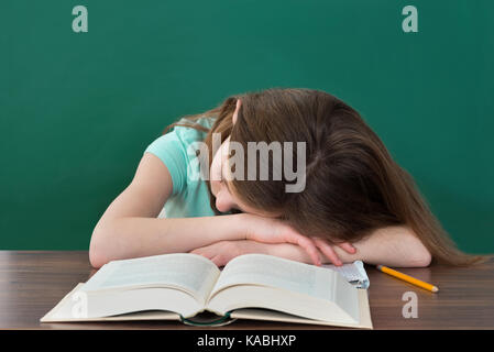 Stanco studente con libri e matita a dormire la scrivania in aula Foto Stock