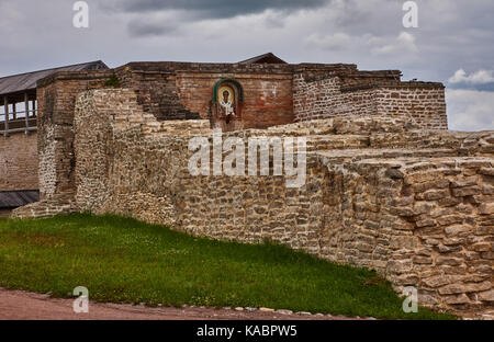 In primo piano è uno spessore di parete di mattoni di una antica fortezza. in background, un'icona ortodossa e un frammento della galleria coperta sono visibili. Foto Stock