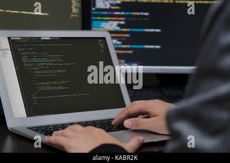 Hacker che lavora su un codice. Il codice di programmazione su schermo. La criminalità su internet concept Foto Stock