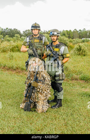 Tre membri della contea di Hillsborough Sheriff's Office SWAT team, con ingranaggio completo e uno in una Ghillie Suit pronto per una giornata della formazione delle forze di polizia. Foto Stock