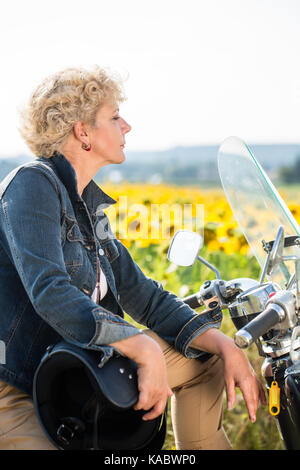 Active senior donna che indossa un denim blu con camicia mentre è seduto sul Foto Stock