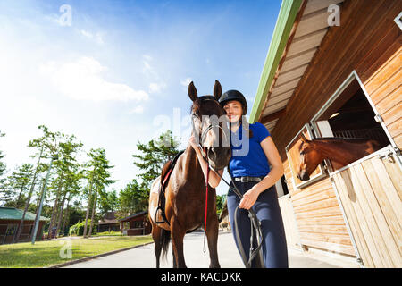 Felice ragazza jockey abbracciando la sua baia di razza cavallo Foto Stock