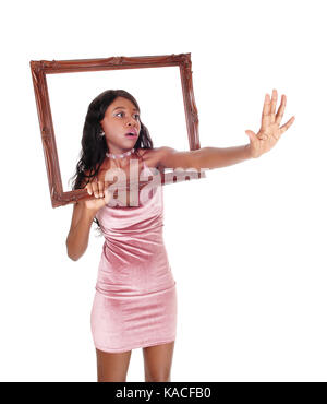 Un molto turbato donna africana in un abito rosa di raggiungere attraverso una cornice immagine, dicendo stop, no, isolato per sfondo bianco Foto Stock