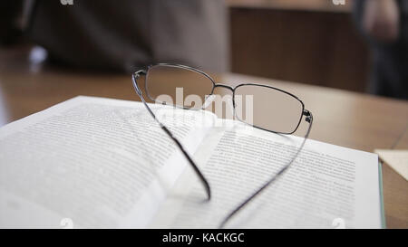 Notebook bianco con gli occhiali sul tavolo di legno. bicchieri insegnante sul tavolo Foto Stock