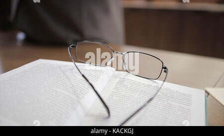 Notebook bianco con gli occhiali sul tavolo di legno. bicchieri insegnante sul tavolo Foto Stock