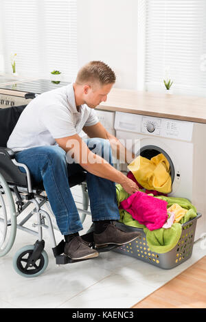 Giovane uomo disabili su sedia a rotelle di mettere gli asciugamani in  lavatrice Foto stock - Alamy