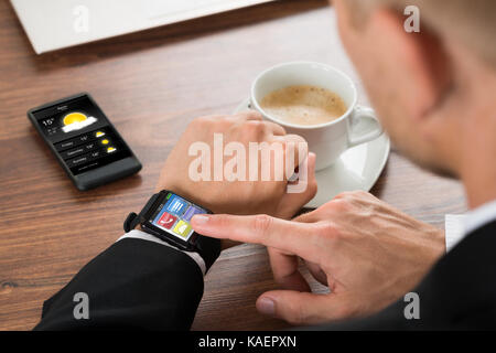 Close-up di un imprenditore il controllo del meteo sulla smartwatch Foto Stock