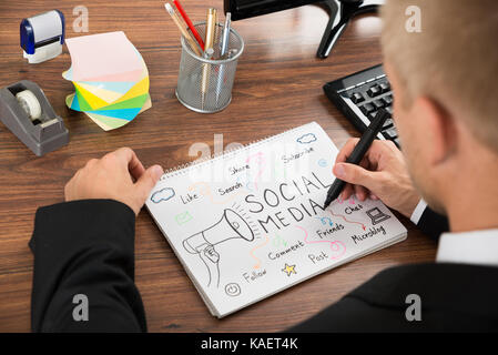 Close-up di imprenditore disegno social media diagramma sul notebook a scrivania Foto Stock
