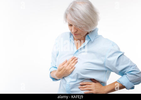 Grigio-dai capelli donna affetta da stomachache Foto Stock