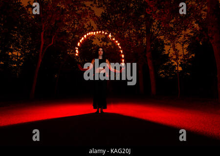 Strega a giocare con le luci come fuoco nella foresta durante il periodo di halloween Foto Stock