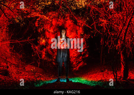 Strega a giocare con le luci come fuoco nella foresta durante il periodo di halloween Foto Stock