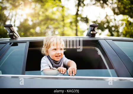 Little Boy giocando in auto, proteso al di fuori della finestra. Foto Stock