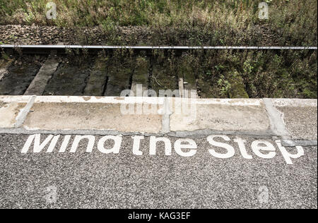 Mente il passo dipinta sulla stazione ferroviaria piattaforma. Regno Unito Foto Stock