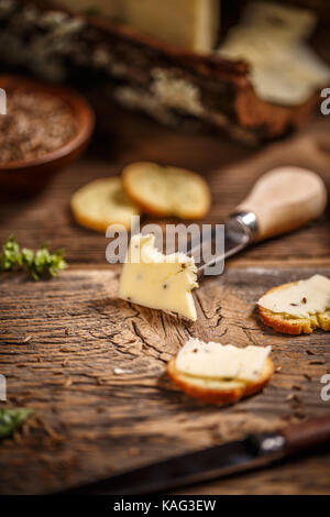 Formaggio con semi di cumino sul vecchio sfondo di legno Foto Stock