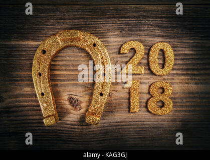 Felice anno nuovo 2018 concept. numeri di oro e il ferro di cavallo sullo sfondo di legno Foto Stock